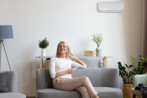 older-woman-on-couch-relaxing-with-heat-pump-on-wall