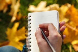 writing-in-notepad-with-pen-with-fall-leaves-behind