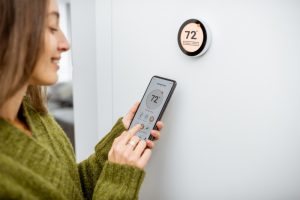 person-setting-thermostat-with-phone-app